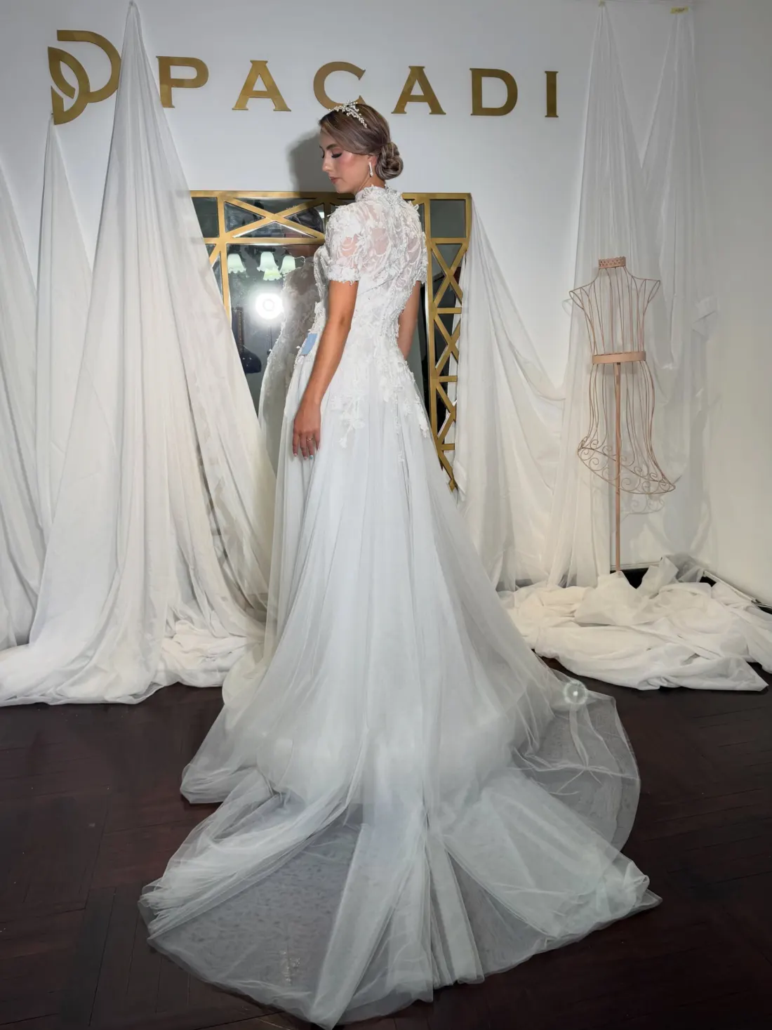 Asesora de PACADI ajustando un vestido de novia frente al logo de la tienda